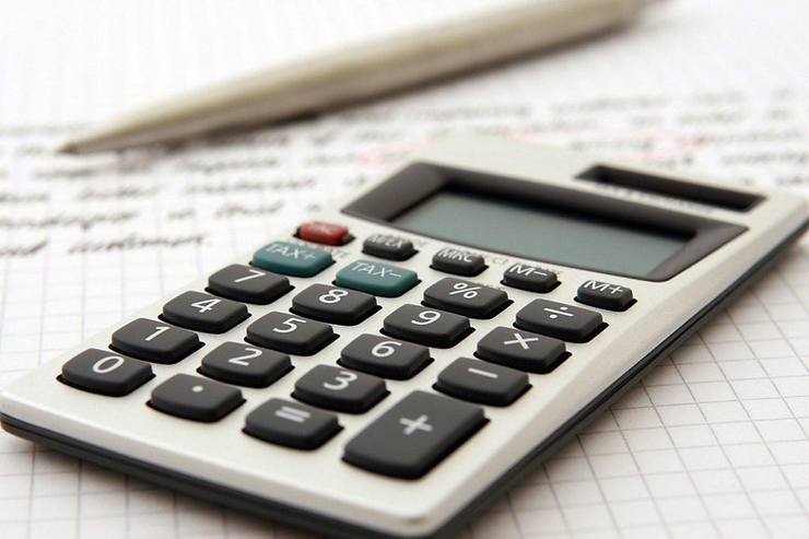 Close-up of a calculator resting on a sheet of financial figures with a pen.