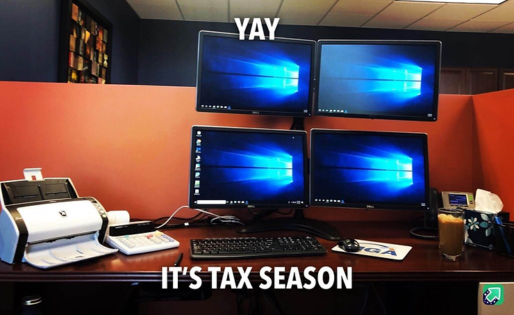 Humorous photo of an office desk with four monitors and a document scanner, captioned 'Yay, it's tax season'.