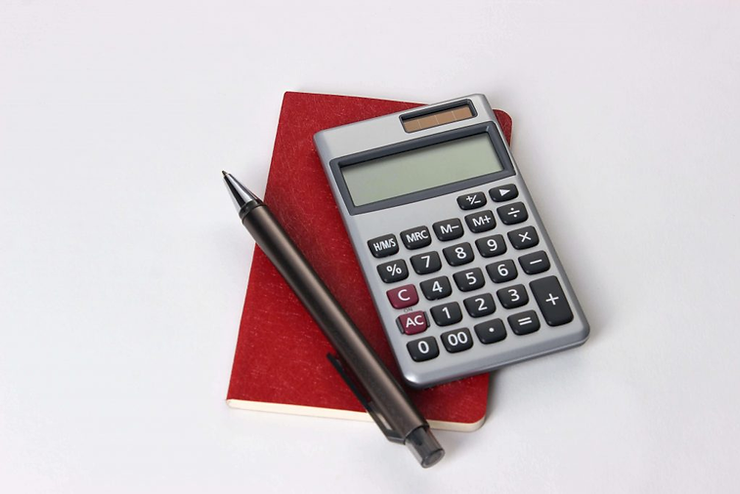 Calculator and pen on a red notebook against a white background. The calculator displays various function keys, creating a studious mood.