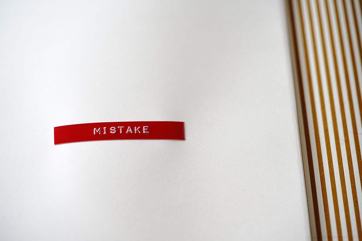 Red label reading "MISTAKE" on a white background with gold striped edge, conveying a sense of error or oversight.